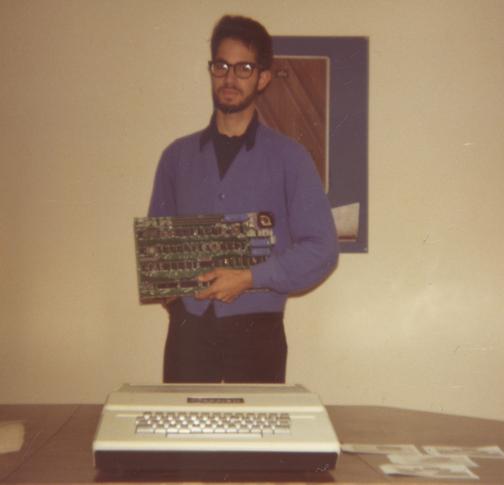 Bill Fernandez holds an Apple I, with an Apple II on the desk.  Photo courtesy of Bill Fernandez